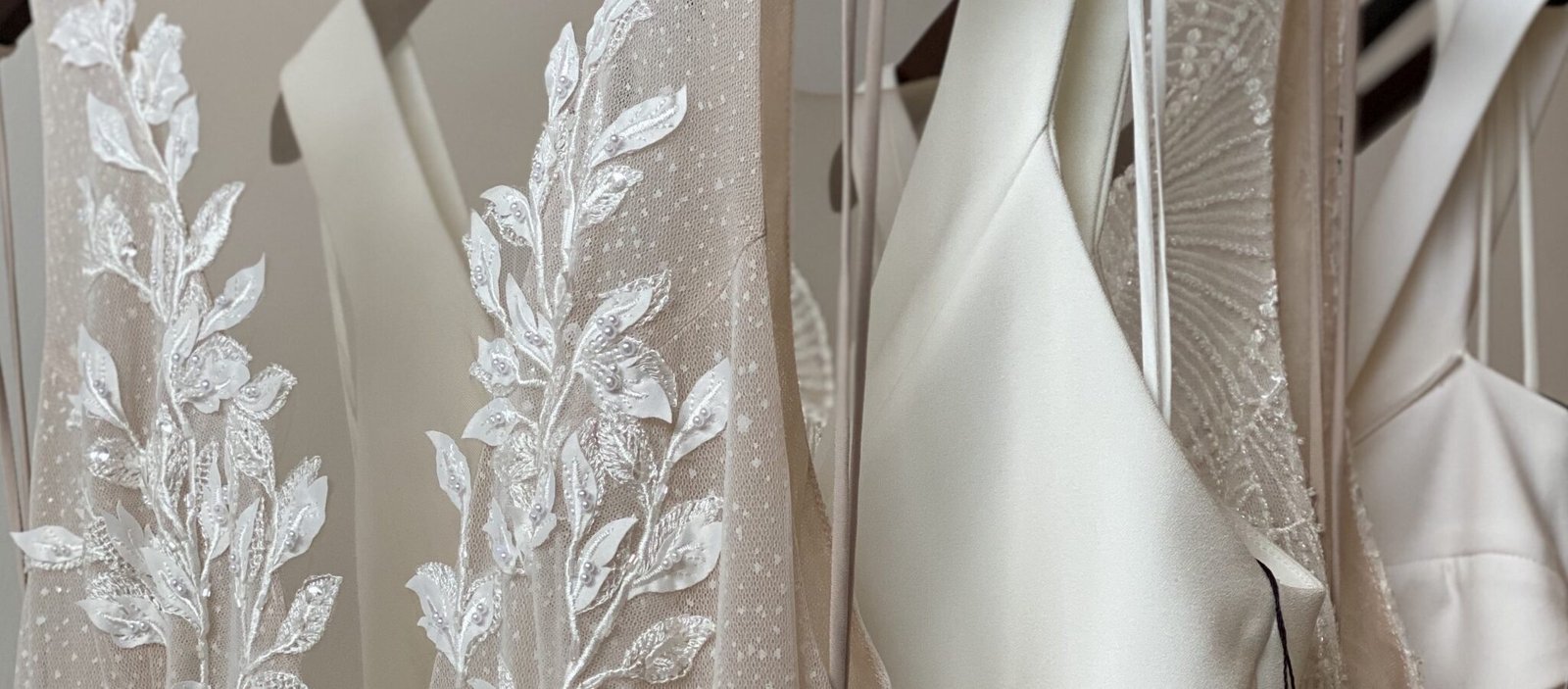 Close Up on the lace detail of the Mimi, Blake, Bobbie, Ellington, Airlie and Ace wedding dresses by Jane Hill Bridal hung on a rail at Kiva and Zen Bridal Devon